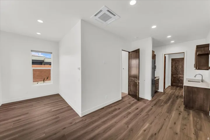 Wood-finish flooring, recessed lighting, white walls, and dark wood doors