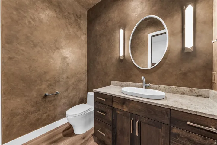 Vanity with stone countertop, vessel sink, and wood-finish cabinetry