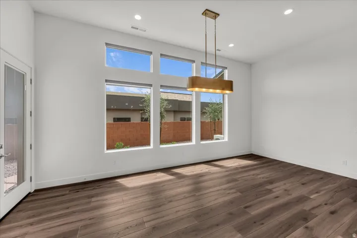 Dark wood-finish flooring with a modern linear chandelier and recessed lighting