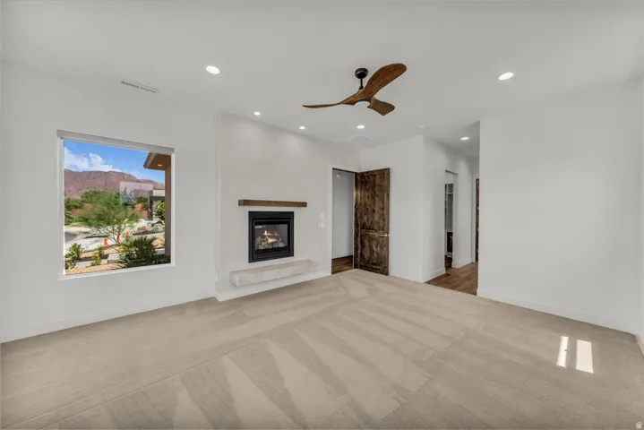 Recessed lighting, wood-finish ceiling fan, built-in fireplace with a floating mantel, and a window with roller shade