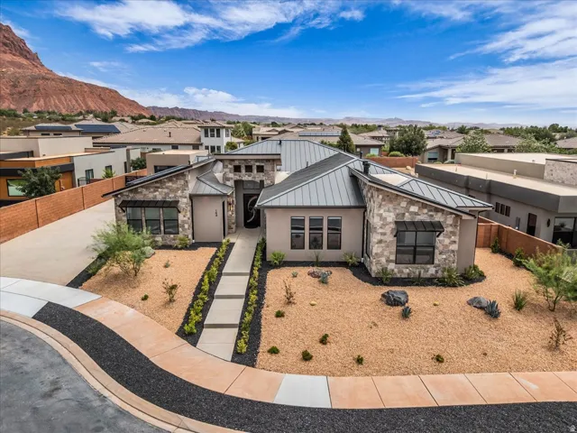 Contemporary architecture featuring a stone and stucco exterior, a metal roof, and xeriscaped landscaping