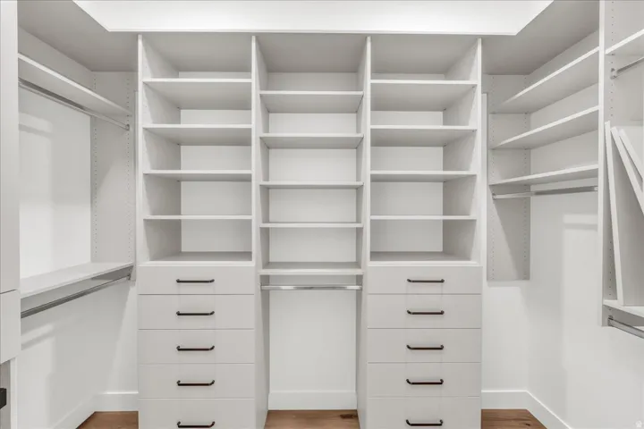 Custom closet system featuring built-in shelving, multiple hanging rods, and integrated drawer units with matte black hardware