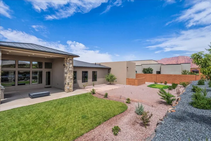 Expansive backyard featuring a covered patio, manicured lawn, gravel landscaping, and a putting green