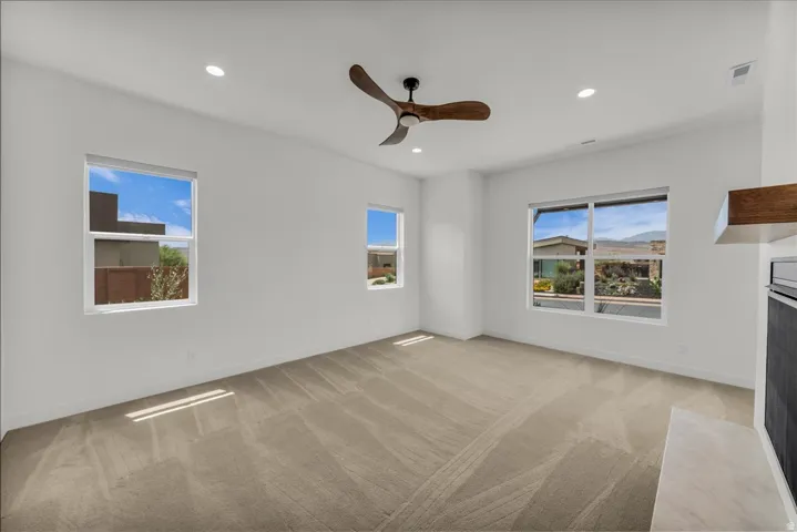 Recessed lighting, ceiling fan, multiple windows, fireplace with hearth, and wood-finish mantle