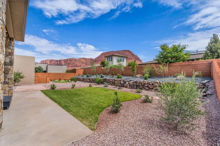 Expansive backyard featuring a manicured lawn, established landscaping, and a substantial retaining wall