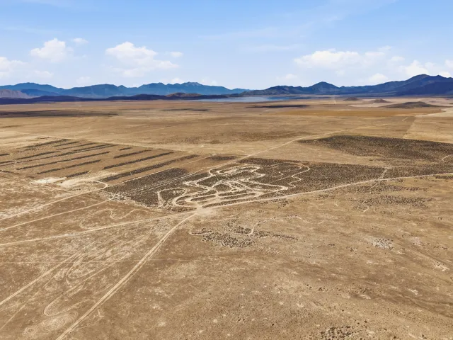 Expansive desert terrain with distant mountain ranges and a body of water