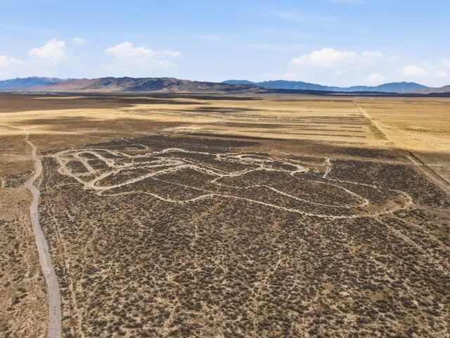 Expansive undeveloped land featuring a dirt road and distant mountain ranges