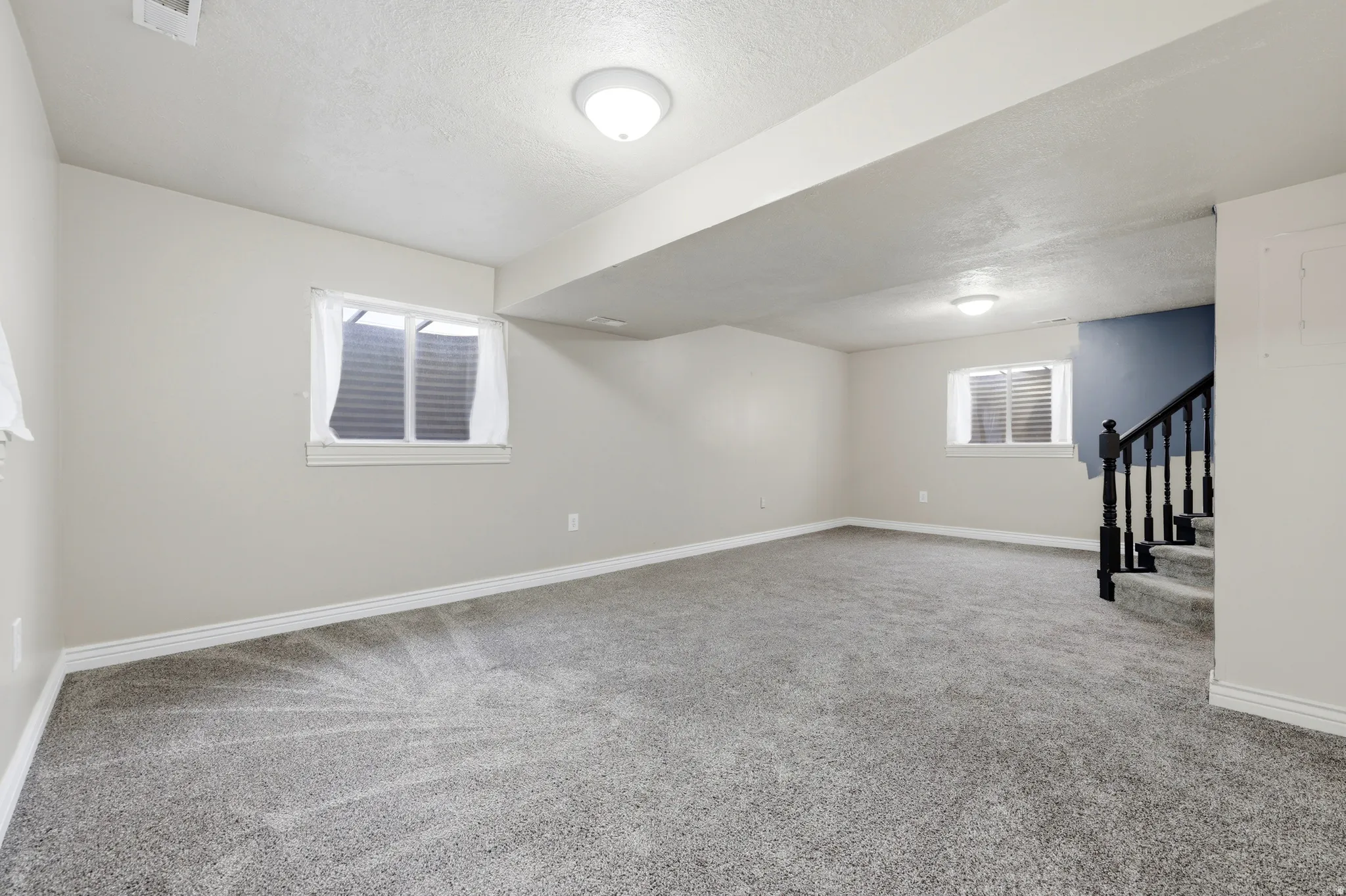 Spacious room featuring neutral carpeting, light-toned walls, and multiple windows