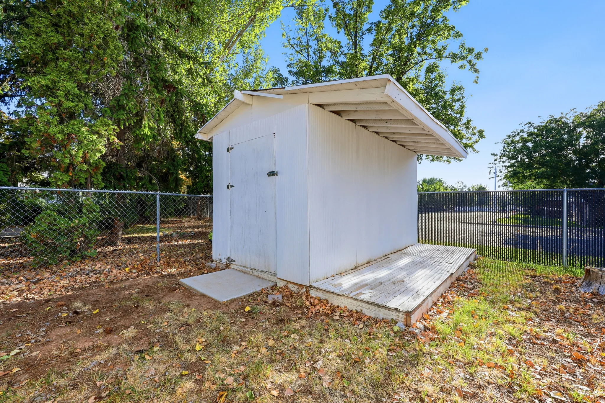 Storage shed with a pitched roof, double doors, and an attached wooden deck