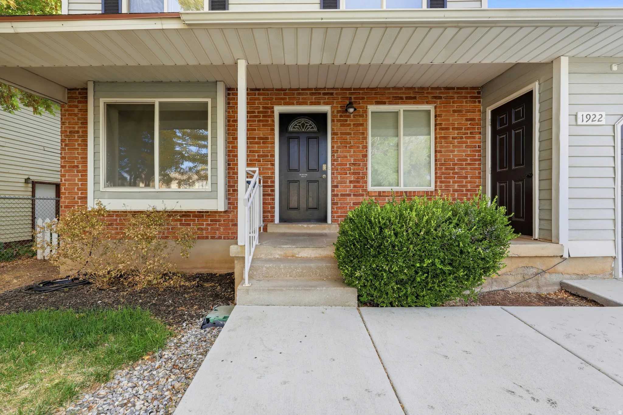 Welcoming front entrance featuring a brick exterior, covered porch with columns, and concrete walkway