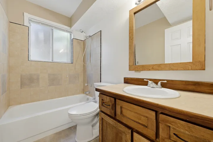 Built-in vanity with a drop-in sink, natural wood-finish cabinetry, and a framed mirror