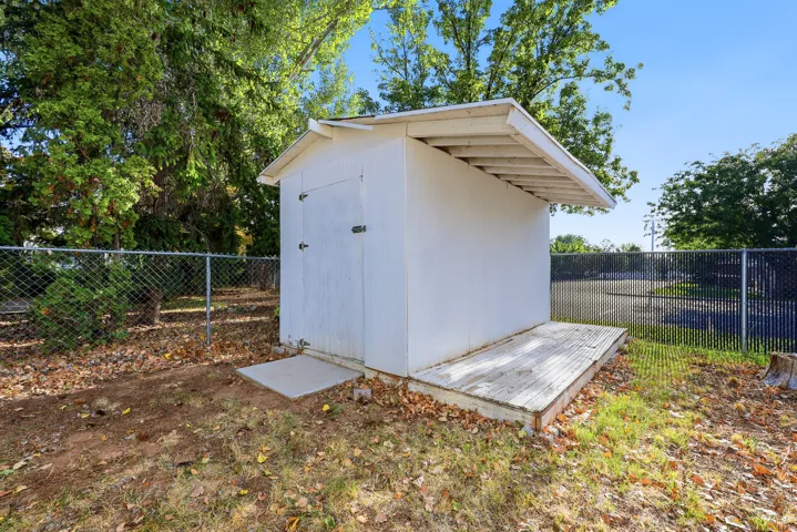 Storage shed with a pitched roof, double doors, and an attached wooden deck