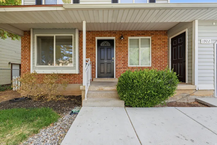 Welcoming front entrance featuring a brick exterior, covered porch with columns, and concrete walkway