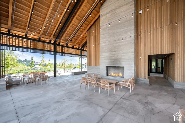 Vaulted wood-clad ceiling with exposed beams, concrete flooring, built-in fireplace, and wood-paneled walls