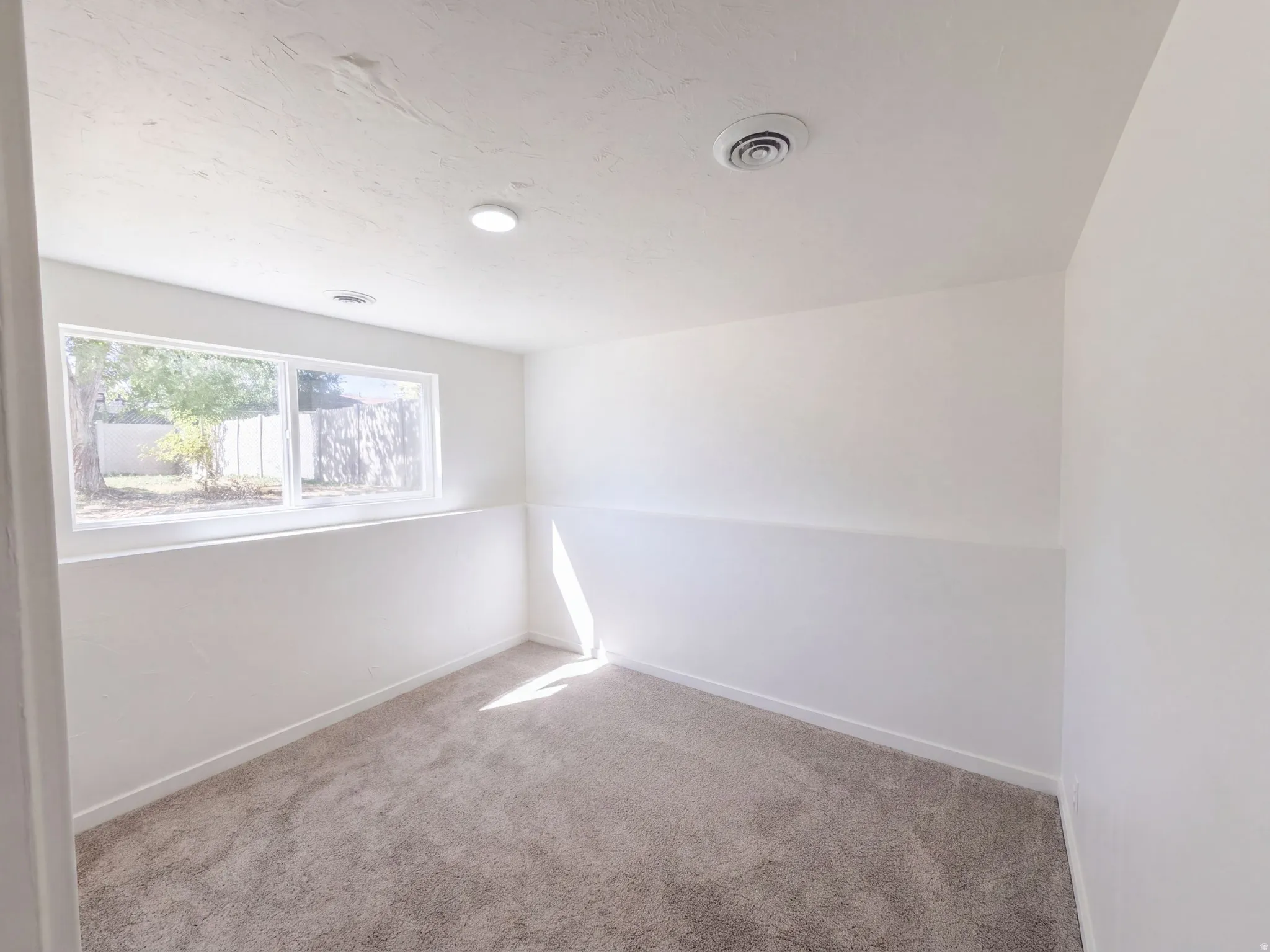 Recessed lighting, white paint finishes, light-toned carpet, and a large window