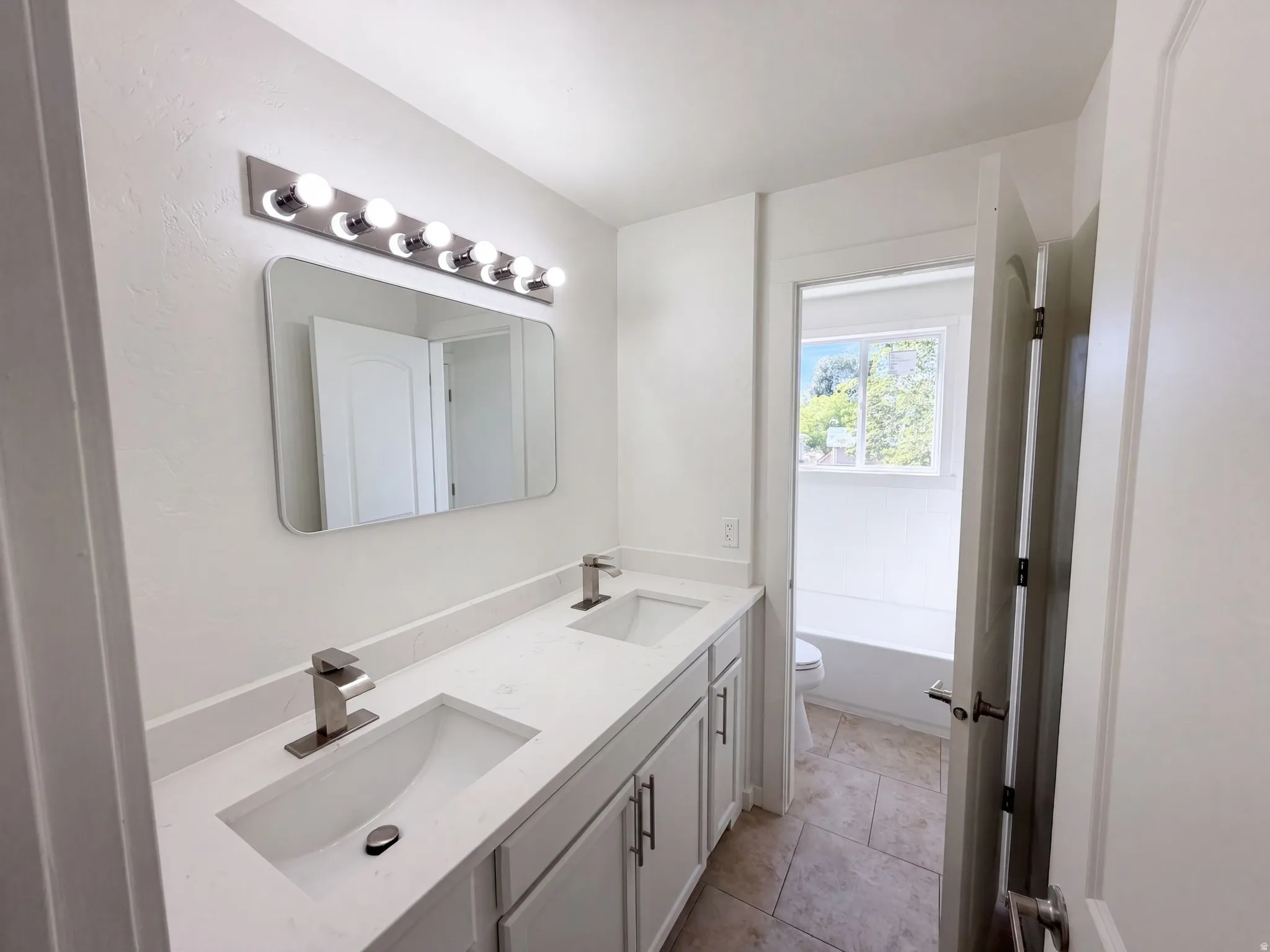 Double vanity with undermount sinks, stone countertops, and brushed nickel fixtures