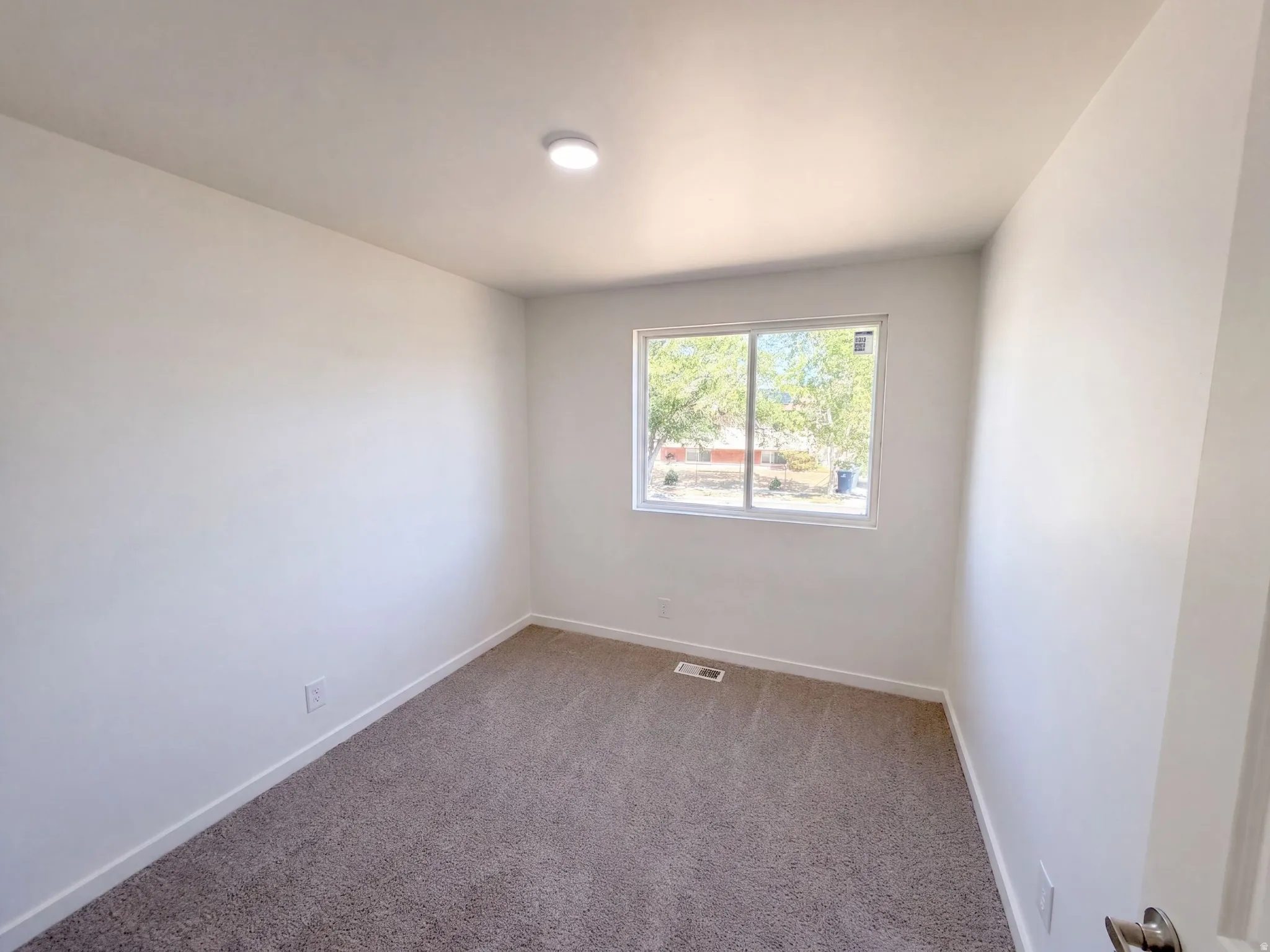 Neutral tone walls with recessed lighting and a window
