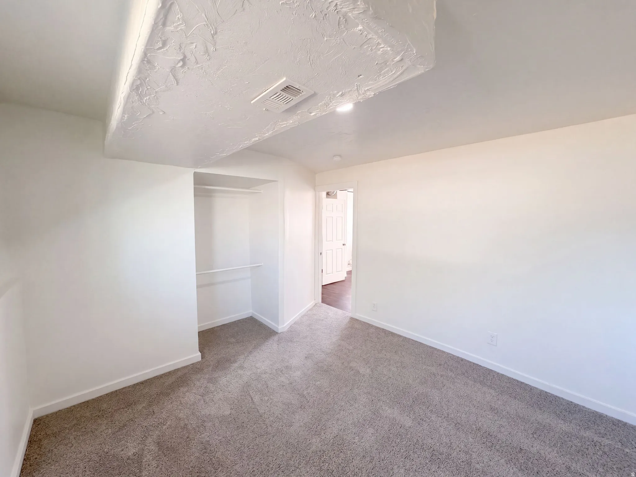 Recessed lighting, light-toned walls, and neutral carpeting
