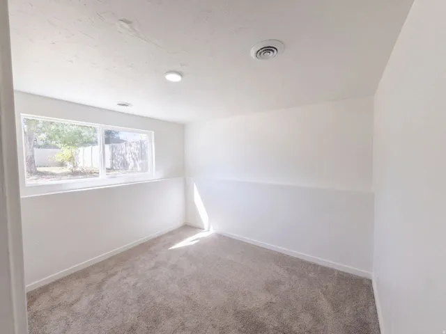Recessed lighting, white paint finishes, light-toned carpet, and a large window