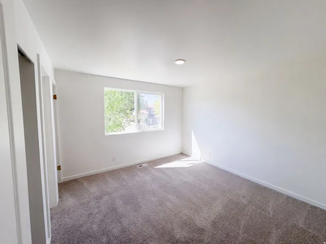 Wall-to-wall carpeting and white walls in a bright room with a single window