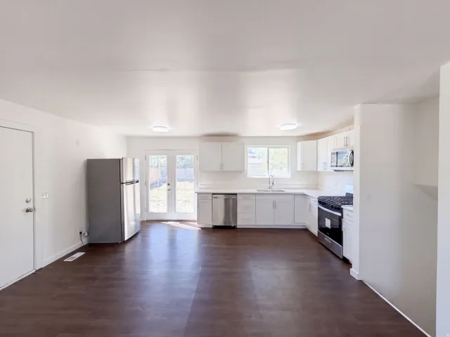 Open-concept kitchen featuring white cabinetry, stainless steel appliances, and a light-colored countertop