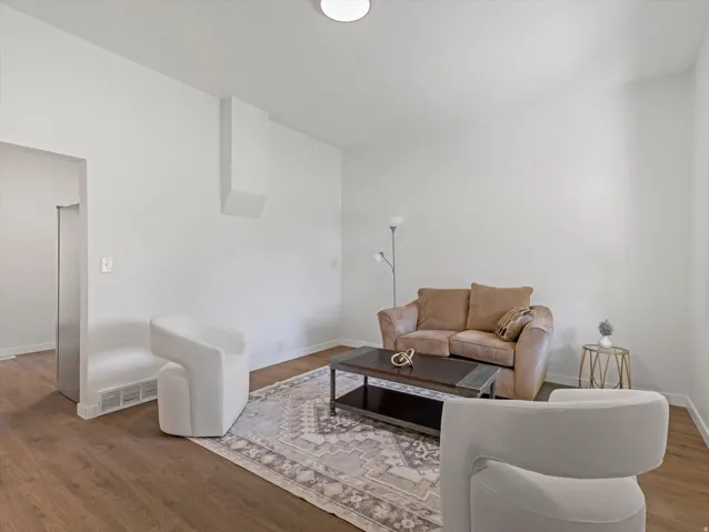 Wood-finish flooring, white walls, and a flush-mount ceiling light