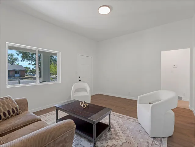 Recessed ceiling light, white painted walls, wood-finish flooring, white window frames, and a white paneled door