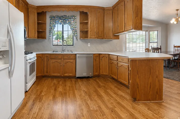 Kitchen featuring wood-finish flooring, wood cabinetry, white countertops, and a stainless steel dishwasher