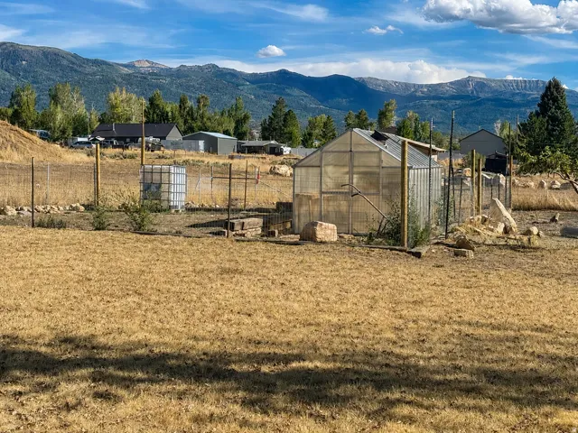 Fenced property with a greenhouse structure, a storage shed, and mountain scenery