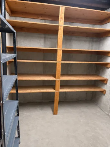 Built-in wood shelving with multiple tiers, set against concrete walls and a concrete floor