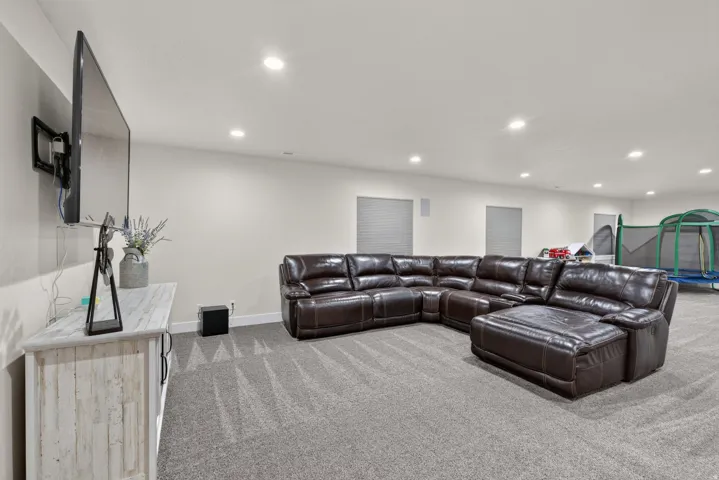 Recessed lighting, wall-mounted television, and neutral-toned walls