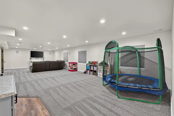 Spacious room featuring recessed lighting, wall-mounted speakers, and multiple windows with blinds