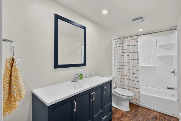 Navy blue vanity with a white countertop, chrome faucet, and wood-finish flooring