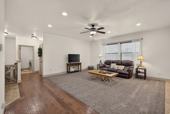 Spacious living area featuring recessed lighting, a ceiling fan, wood-finish flooring, and expansive windows