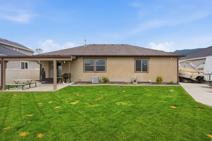Expansive green lawn, stucco exterior, covered patio, concrete patio, and a dedicated concrete drive