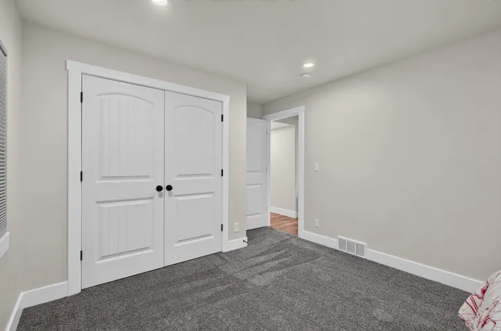 Neutral-toned walls, recessed lighting, and grey carpeting