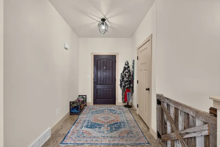 Arched panel entryway door with dark finish, light-toned walls, and wood-finish flooring