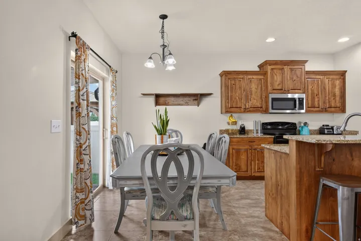 Kitchen with wood cabinetry, stainless steel microwave, stone countertops, and tile flooring