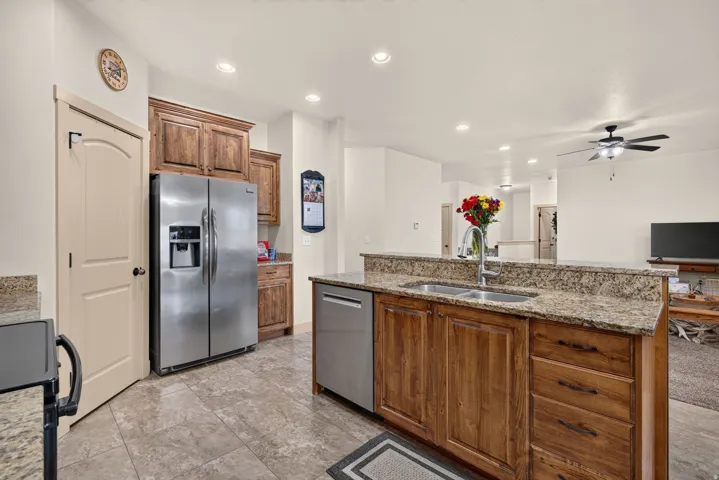 Kitchen featuring wood cabinetry, stainless steel appliances, speckled stone countertops, a double basin sink, and recessed lighting