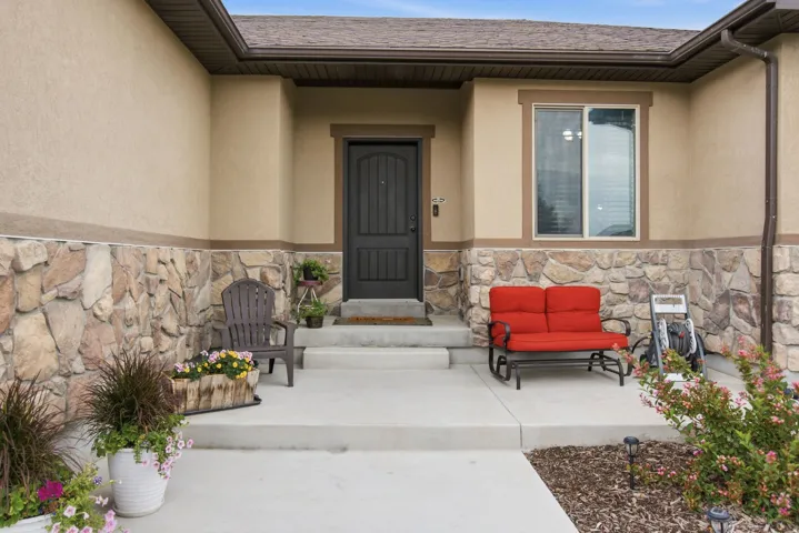Stucco and stone facade with a dark entry door, framed window, and concrete porch