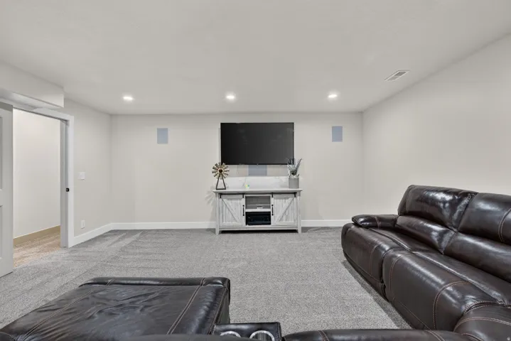Recessed ceiling lighting, wall-mounted speakers, and light-colored carpeting