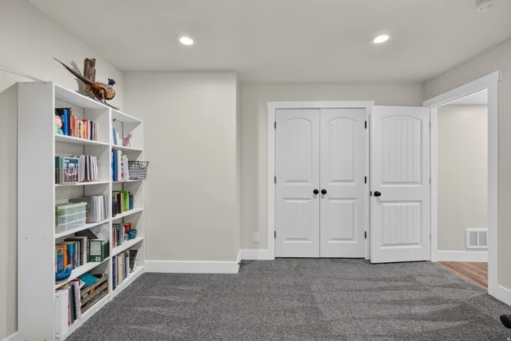Recessed ceiling lighting, built-in shelving, white paneled doors, and grey carpet