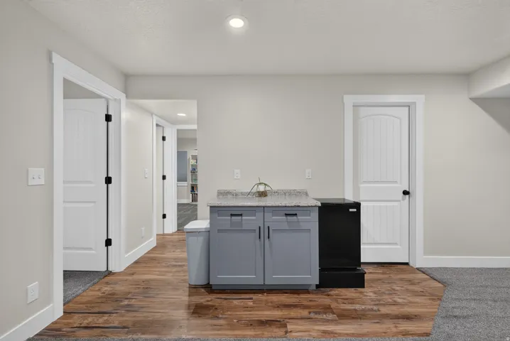 Wood-finish flooring, recessed lighting, white interior doors, and built-in cabinetry with a stone-finish countertop