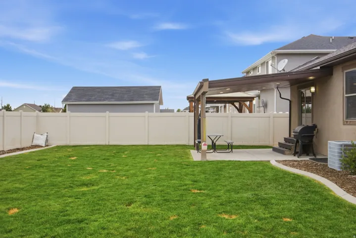 Expansive green lawn, private fencing, covered patio, concrete patio, and exterior lighting