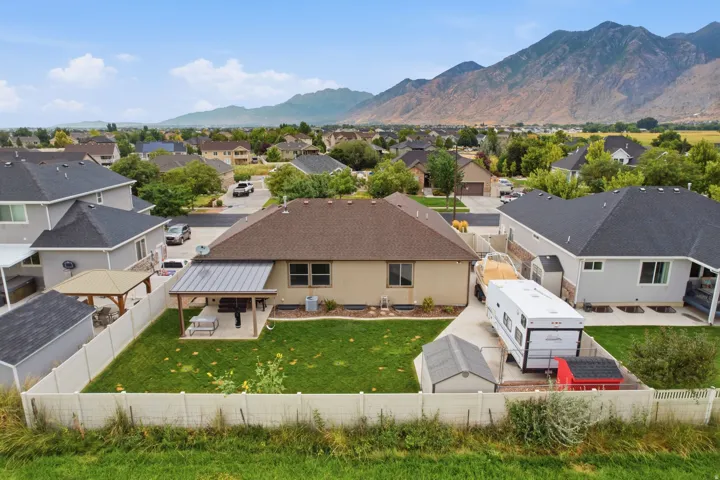 Expansive backyard featuring a covered patio, manicured lawn, and privacy fencing