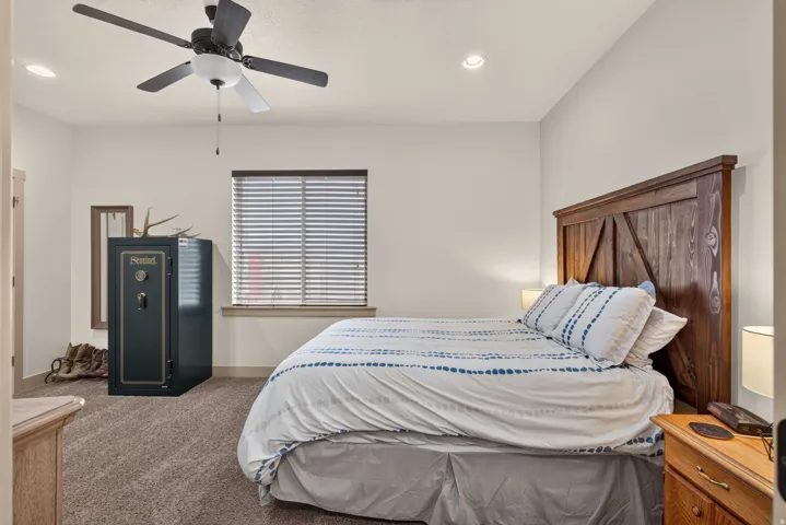Carpeted bedroom featuring a wooden headboard, window with blinds, ceiling fan, and recessed lighting