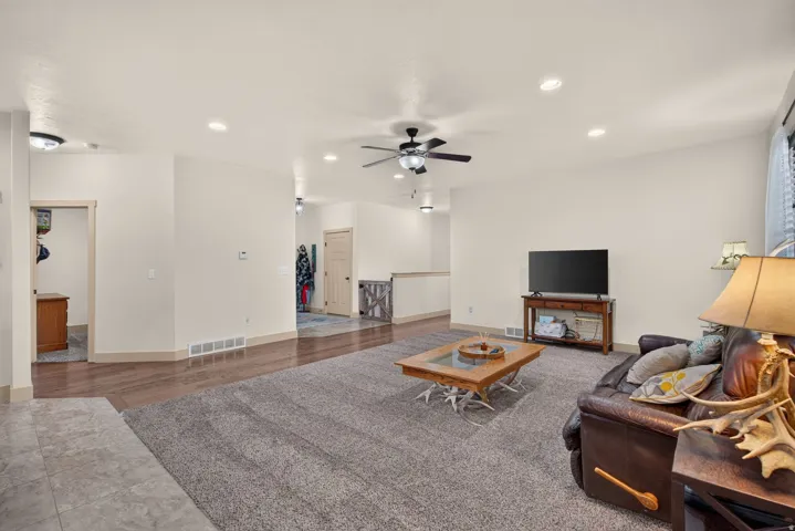 Expansive living area with recessed lighting, wood-finish flooring, and ceiling fans