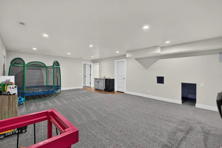 Spacious room with recessed lighting, gray carpeting, a built-in wet bar with cabinetry, and a wood-finish flooring section