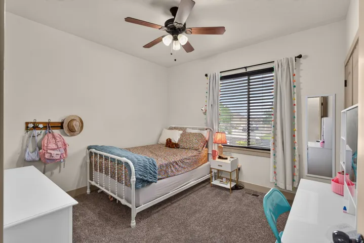 Room featuring a ceiling fan with light fixture, window with blinds, and neutral-toned wall paint