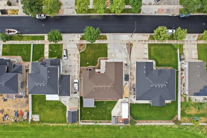 Property with a dark shingled roof, a concrete driveway, and a manicured lawn
